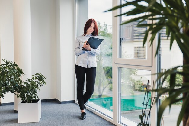 Mädchen posiert mit Zwischenablage im Büro