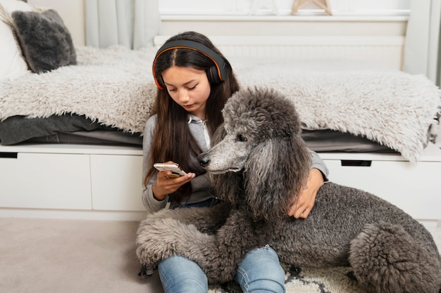 Mädchen schaut auf ihr Handy, während sie auch ihren Hund hält dog
