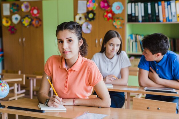 Mädchen schreibt und posiert in der Schule