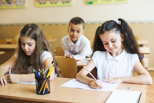 Mädchen sitzen am Schreibtisch im Klassenzimmer schreiben