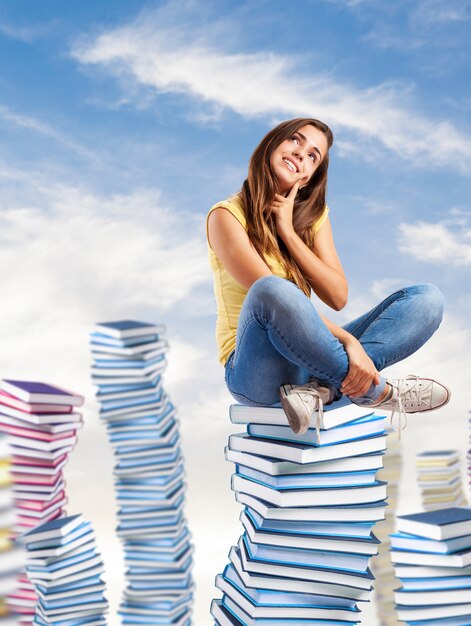 Mädchen sitzen auf Bergen von Bücher und lächelnd