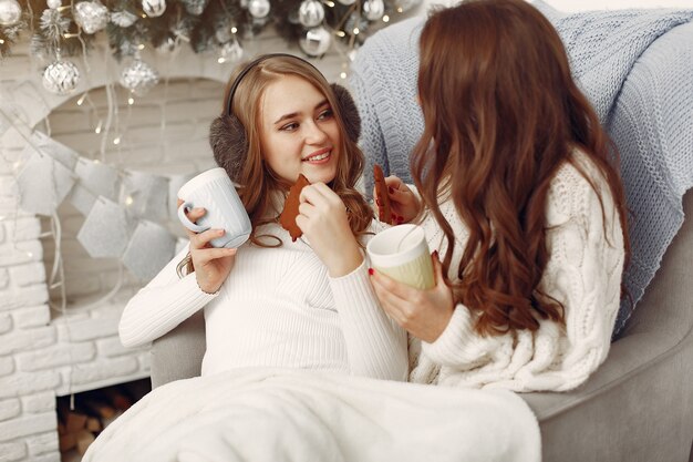 Mädchen sitzen auf dem Stuhl. Frauen mit Tassen. Schwestern bereiten sich auf Weihnachten vor