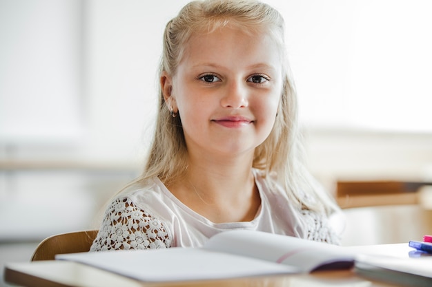 Kostenloses Foto mädchen sitzt am schreibtisch lächelnd