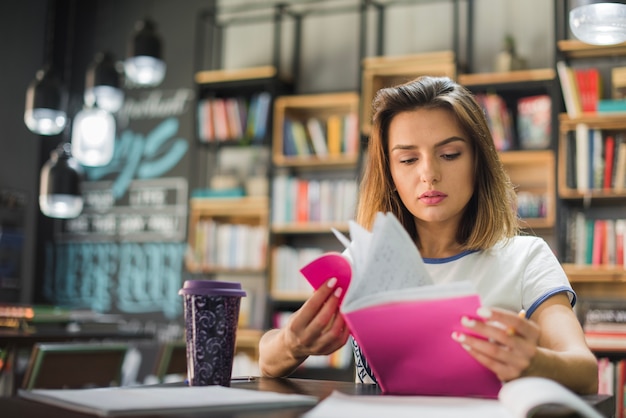 Mädchen sitzt am Tisch in der Bibliothek