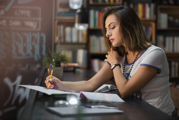 Mädchen sitzt am Tisch mit Notebooks schreiben