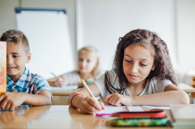 Mädchen sitzt am Tisch schriftlich