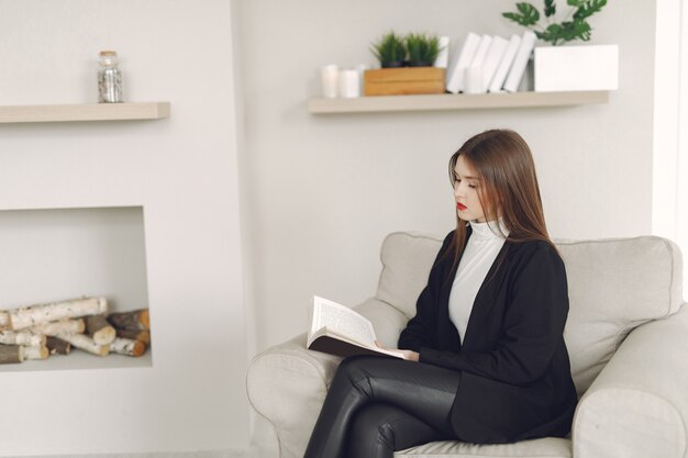 Mädchen sitzt auf einem Stuhl und liest ein Buch