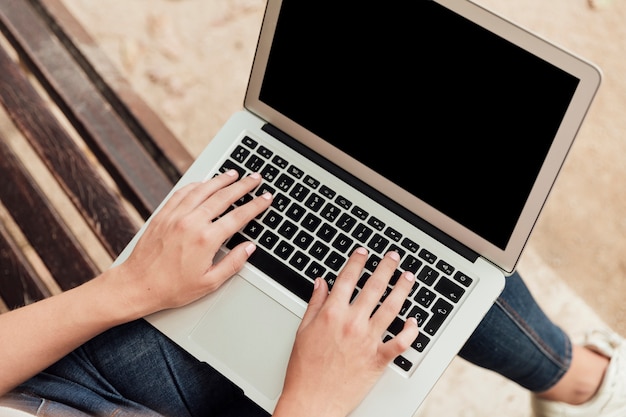 Mädchen sitzt auf einer Bank mit einem Laptop