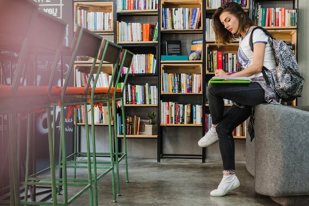 Mädchen sitzt auf Stuhl schriftlich auf Notebook