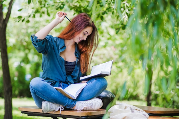 Mädchen sitzt auf tisch im park lächelnd