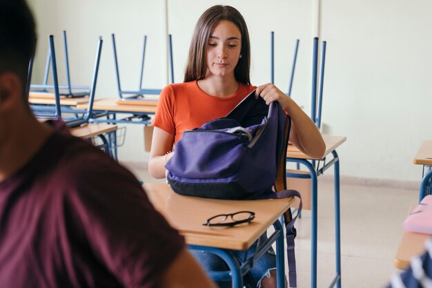 Mädchen sitzt in der Klasse mit ihrem Rucksack