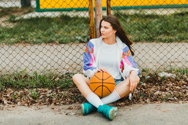 Mädchen sitzt mit Basketball