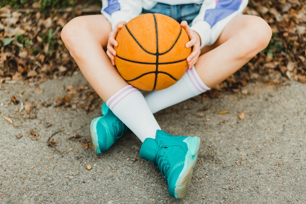 Mädchen sitzt mit Basketball