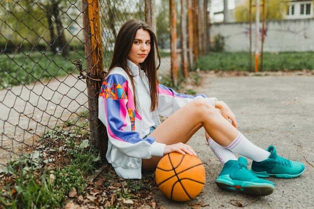 Kostenloses Foto mädchen sitzt mit basketball