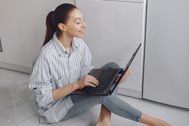 Mädchen sitzt zu Hause und benutzt den Laptop