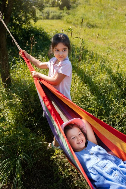 Mädchen spielen zusammen im Freien und sitzen in der Hängematte