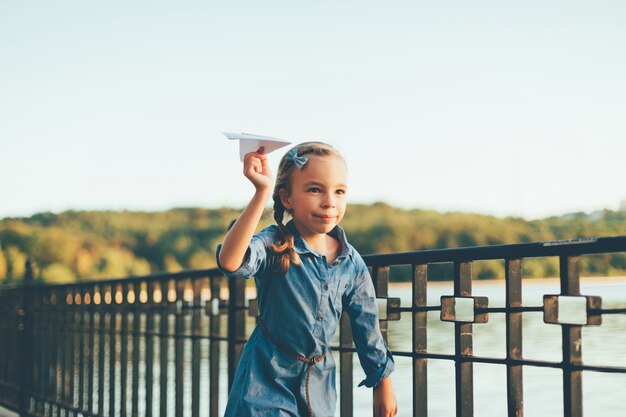 Mädchen spielt, läuft mit Spielzeugpapierflugzeug