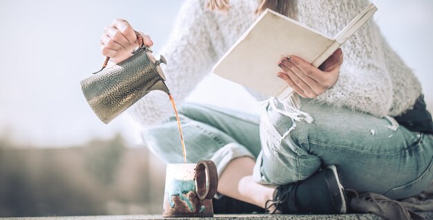 Mädchen trinkt Kaffee und liest Buch im Freien