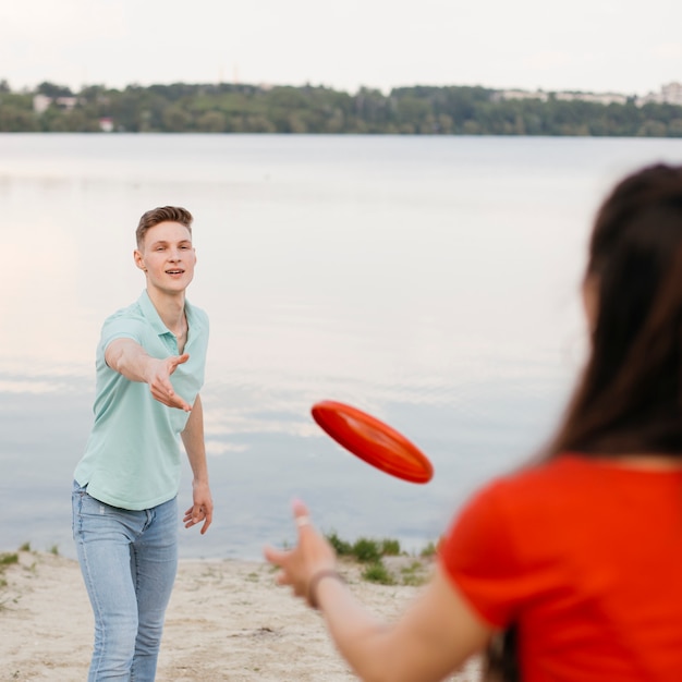 Mädchen und Junge, die mit rotem Frisbee spielen