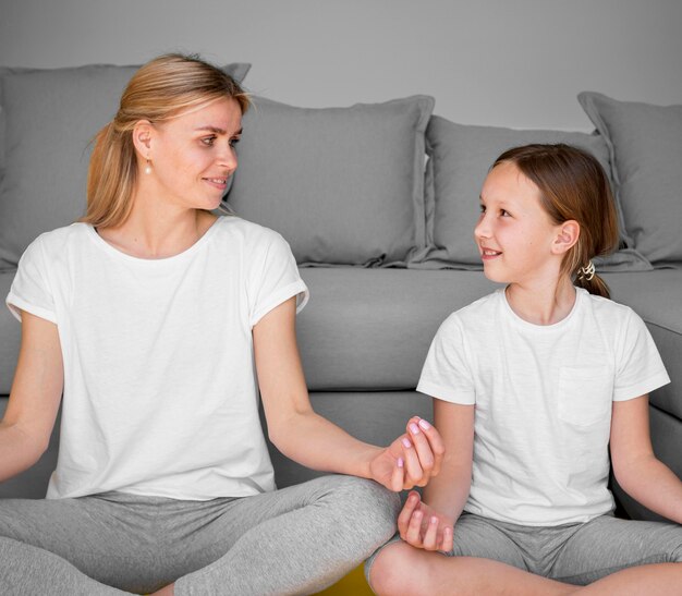 Mädchen und Mutter in der Yoga-Pose, die einander betrachten