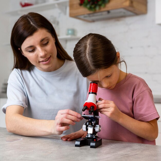 Mädchen und Mutter machen Experimente mit dem Mikroskop