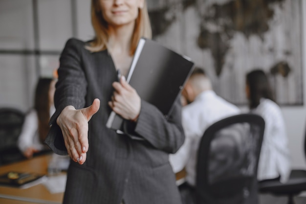 Mädchen unterschreibt die Dokumente. Dame sitzt auf dem Tisch. Manager arbeitet im Büro.