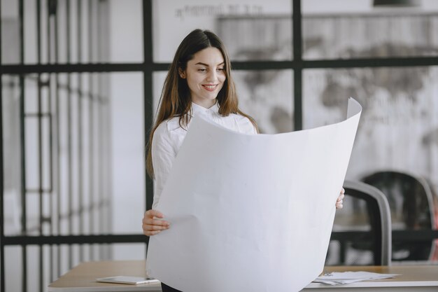 Mädchen unterschreibt die dokumente. dame sitzt auf dem tisch. manager arbeitet im büro.