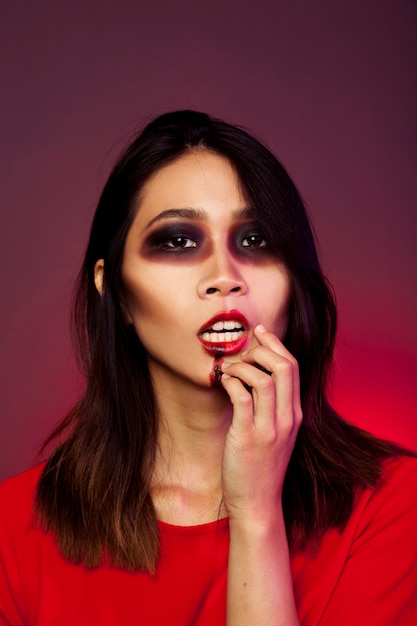 Mädchen verkleidet als Vampir ihren Mund berühren