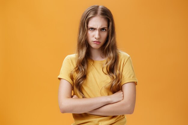 Mädchen verrückt wie der Teufel. Porträt einer wütenden, belästigten und beleidigten hasserfüllten jungen Frau, die unter der Stirn die Stirn runzelt und schmollend die Arme gegen die Brust in defensiver Pose kreuzt und den Täter verachtet.