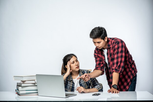 Männer bringen Frauen bei, wie man bei der Arbeit mit Laptops arbeitet.