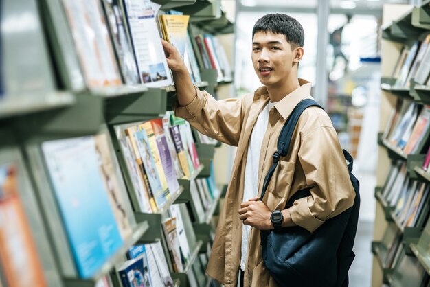 Männer, die einen Rucksack tragen und in der Bibliothek nach Büchern suchen.