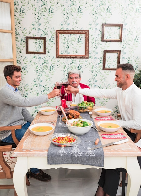 Männer, die Gläser am festlichen Tisch klirren