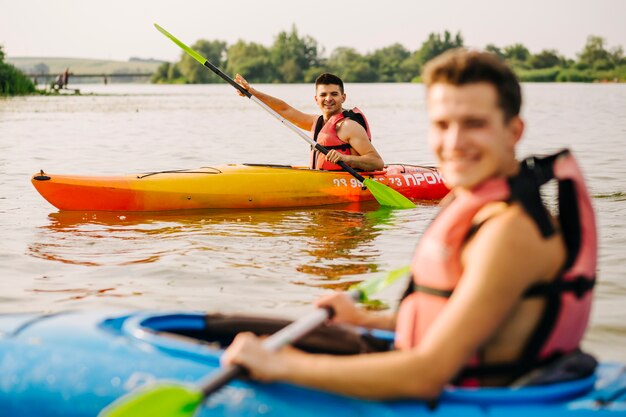 Männer, die mit seinem Freund auf See Kayak fahren