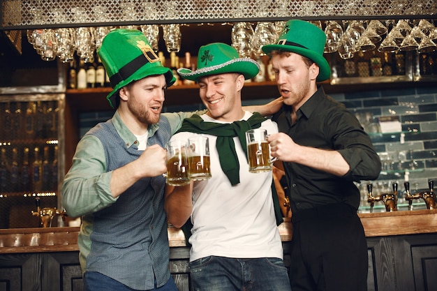 Männer in grünen Hüten. Freunde feiern den St. Patrick's Day. Feier in einer Kneipe.