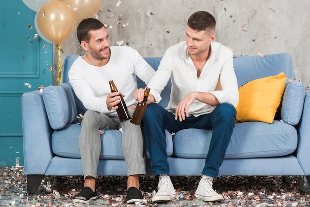 Kostenloses Foto männer mit bier auf blauer couch