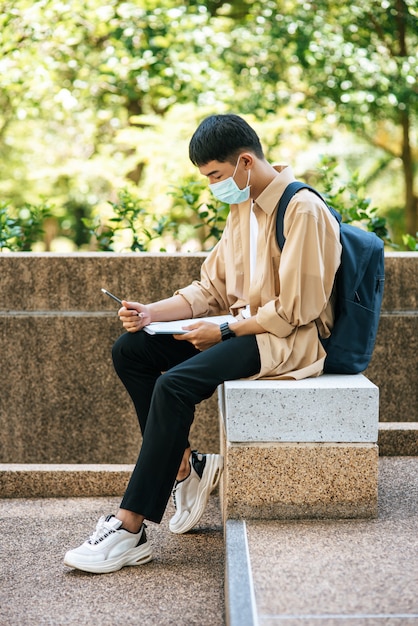 Männer mit Masken sitzen und lesen Bücher auf der Treppe.