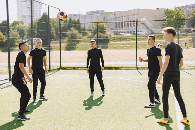 Männer spielen im Park Socer. Turnier auf Mini-Footbal. Kerl in einem schwarzen Sportanzug.