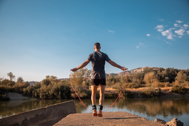 Männertraining mit einem Springseil neben dem Fluss