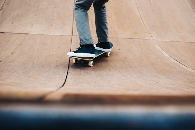 Männliche Beine üben mit Skateboard