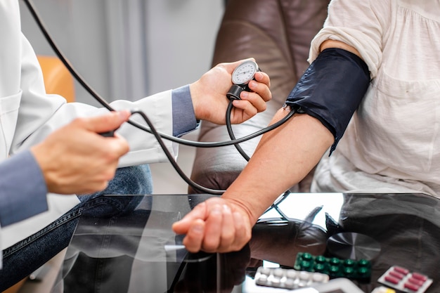 Kostenloses Foto männliche doktorhände, die spannung zu einem patienten messen