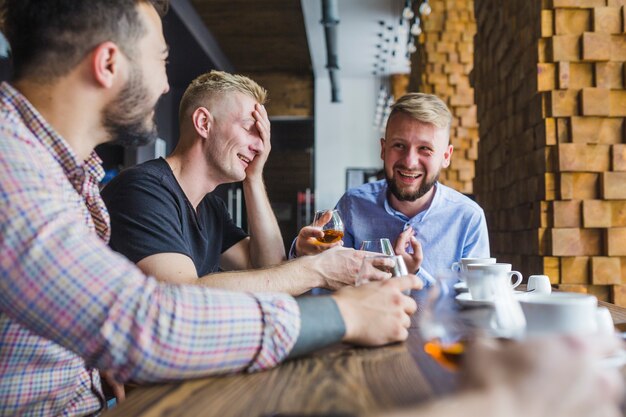 Männliche Freunde, die den Abend genießen, trinkt am Restaurant