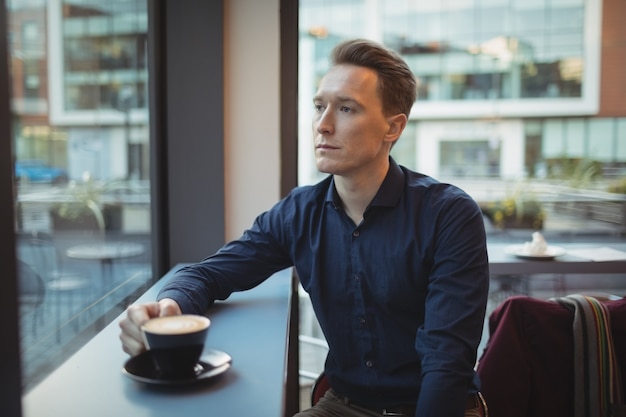 Männliche Führungskraft, die Kaffee am Schalter trinkt