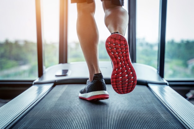 Männliche Füße in Turnschuhen, die auf dem Laufband im Fitnessstudio laufen. Übungskonzept.