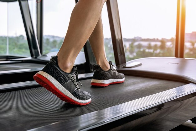 Männliche Füße in Turnschuhen, die auf dem Laufband im Fitnessstudio laufen. Übungskonzept.