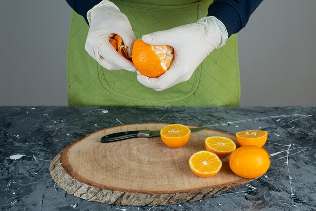 Kostenloses Foto männliche hände, die saftige mandarine auf marmortisch schälen.