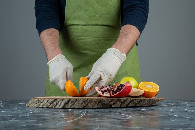 Männliche Hände, die saftige Orange auf Marmortisch halten.