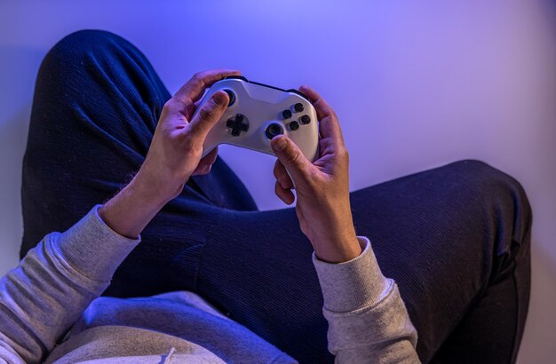 Männliche Hände halten ein Gamepad auf einem blauen Hintergrundkopierraum