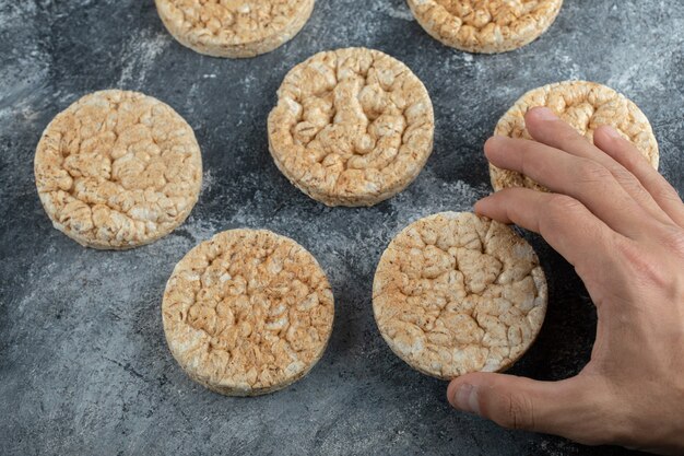 Männliche Hand, die Reiskuchen auf Marmoroberfläche hält