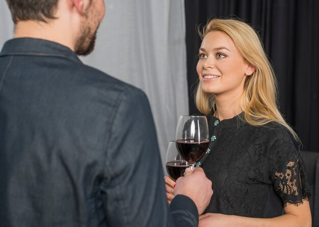 Männliche klirrende Gläser Wein mit fröhlicher Frau im Raum