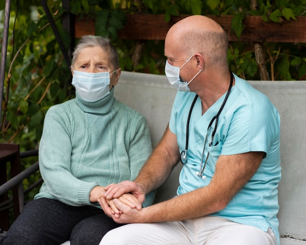 Männliche Krankenschwester, die die Hände der älteren Frau hält